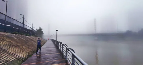 a man is walking on the pier in the fog