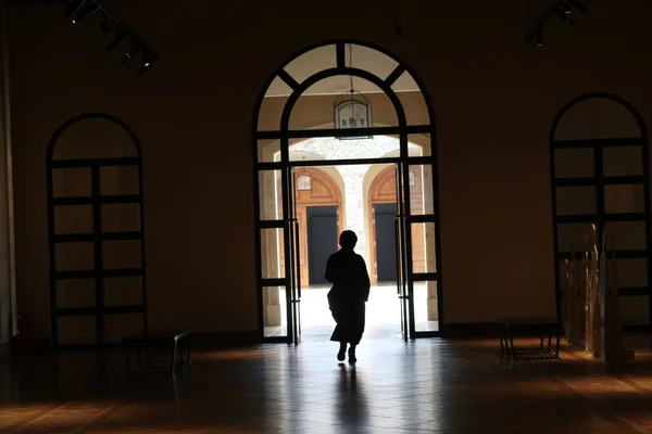 silhouette of a man in a black dress with a window in the background