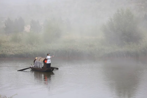 a man in a boat is fishing on the river bank