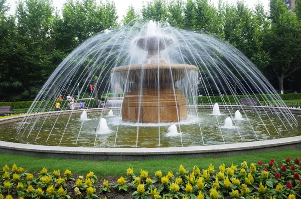 beautiful garden fountain with green grass and a large glass of water
