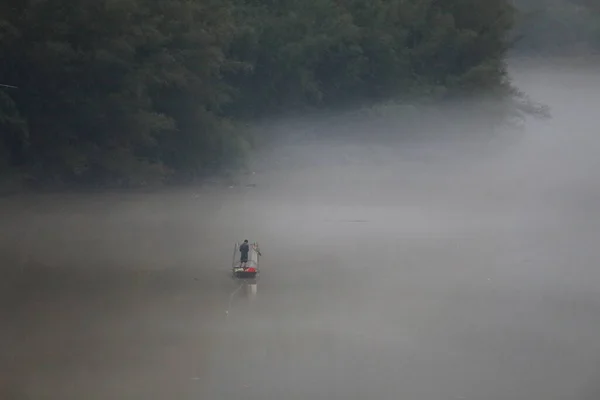 a man in a boat is driving a river in the fog
