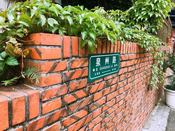 green and red brick wall with a sign of a house