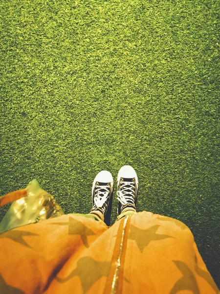 feet of a woman lying on the grass and looking at the camera