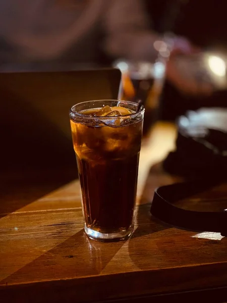 a glass of cola with ice and a cup of coffee