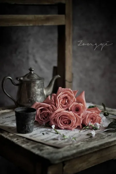 vintage still life with a bouquet of roses and a cup of tea