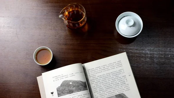 cup of coffee and a book on a wooden table