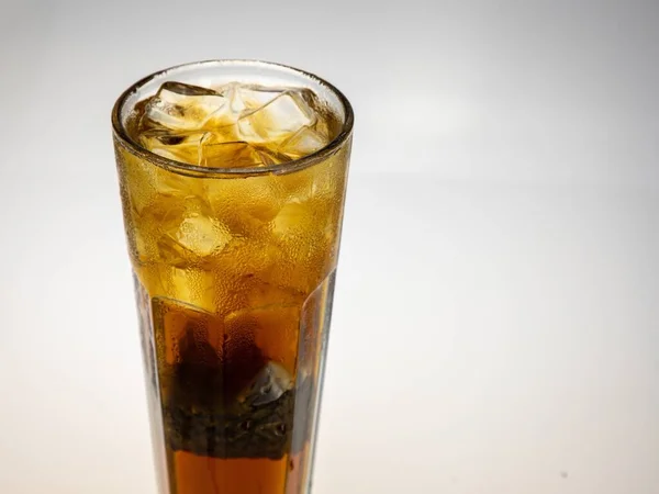 glass of cola with ice cubes on white background