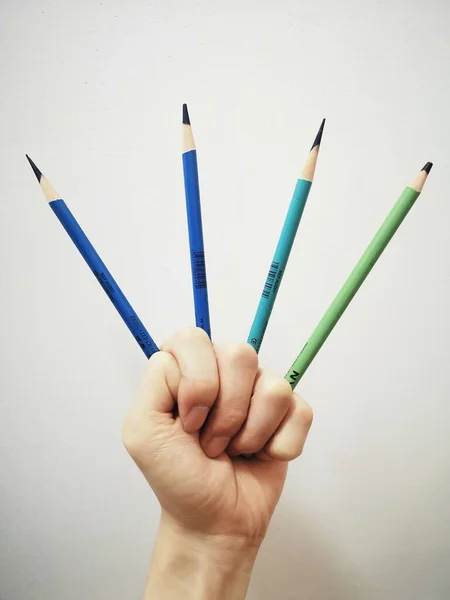 hand holding a pencil and a blue background