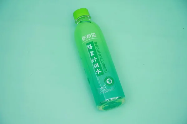 green plastic bottle with a lid and a blue handle on a white background