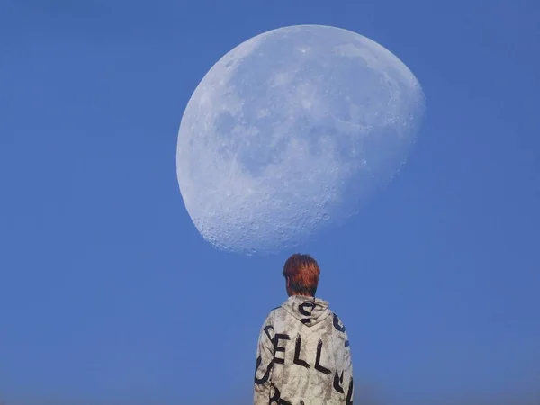 a man in a blue dress with a moon in the sky