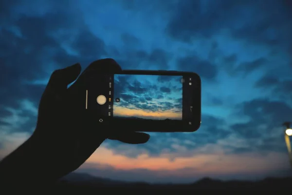 silhouette of a man taking a photo of a mobile phone