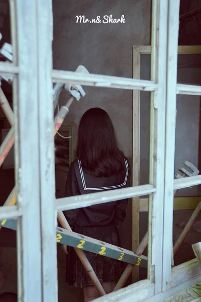 young woman in a white shirt and a black jacket with a wooden fence