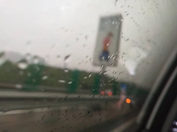 car window with rain drops on the road