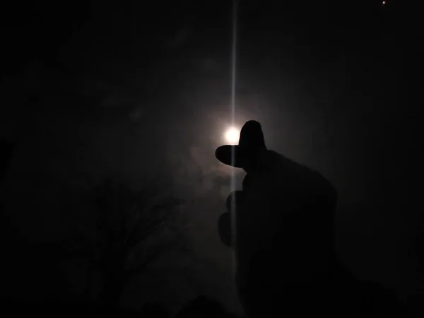 silhouette of man with flashlight on the background of the night sky
