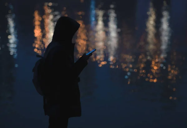 silhouette of a man with a hood on the background of the night sky