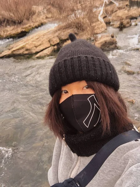 a young woman in a protective mask and a scarf on the background of the forest