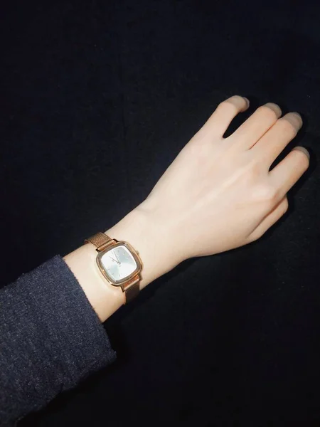 female hand with black watch on a dark background