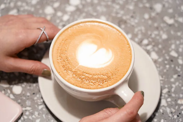 a cup of cappuccino with a white foam in a hand