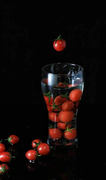 fresh tomatoes and cherry tomato on black background