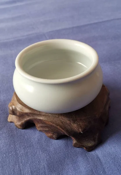 a bowl of white ceramic bowls with a blue lid and a cup of tea on a wooden background