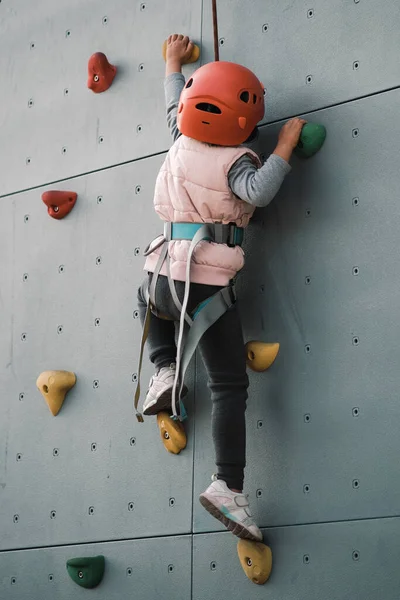 a young girl climbing a rope in a gym