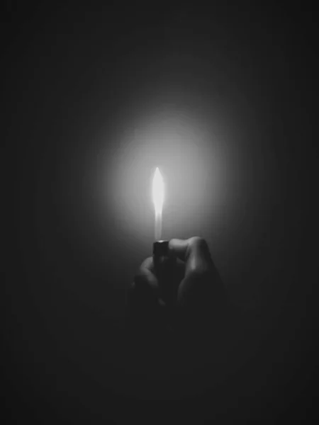 burning candle in hand on black background