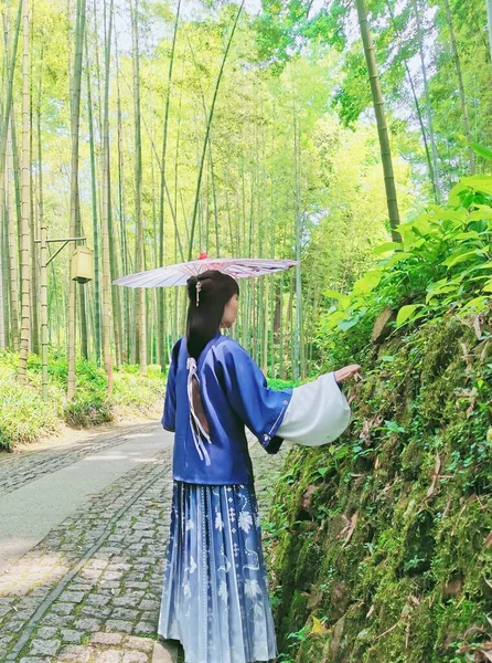 young woman in a green dress with a bag of bamboo