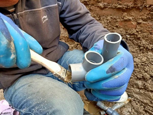 worker in protective gloves and a blue shirt and a white helmet in the garden