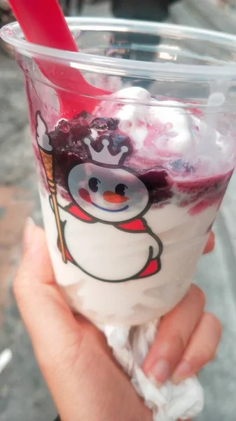 close up of a glass of ice cream with a red straw in a white cup