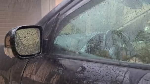 雨正滴在黑色的车上 雨落在车窗上 从后视镜上滴下 — 图库视频影像