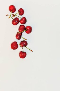 Kırmızı kirazlar, beyaz arkaplanda, üst görünümde.