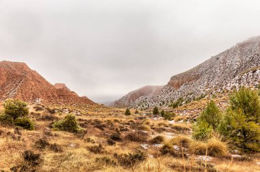 Koyu mavi gökyüzüne karşı kısmen karla kaplı kahverengi dağlar