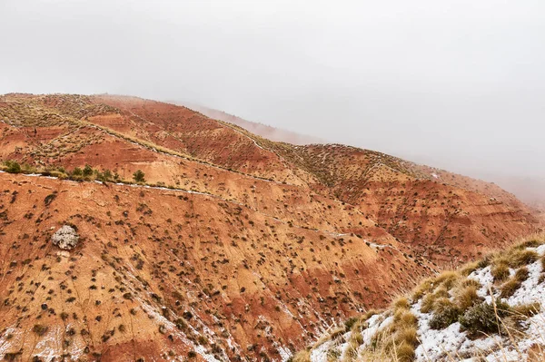 Montañas marrones parcialmente cubiertas de nieve contra un cielo azul oscuro — Foto de Stock