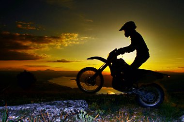Una imagen de un motociclista haciendo un truco y saltando en aire.