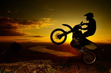 Una imagen de un motociclista haciendo un truco y saltando en aire.