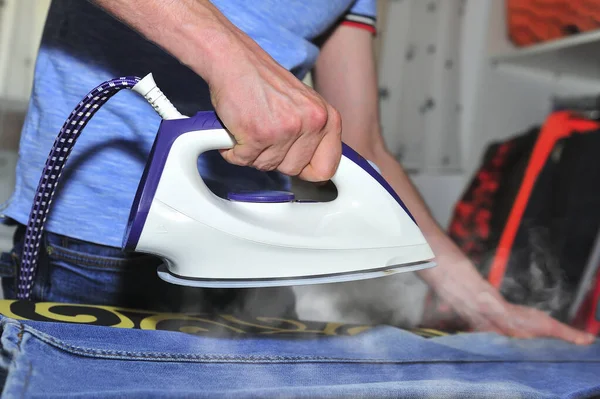 Young Man Steam Ironing Some Jeans — Stock Photo, Image