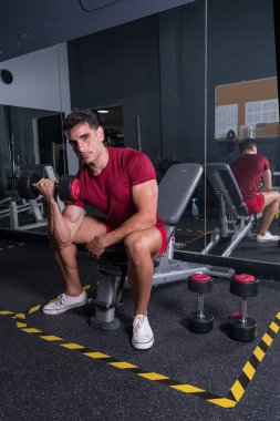 Genç bir çocuk spor salonunda pazılarını çalıştırıyor..
