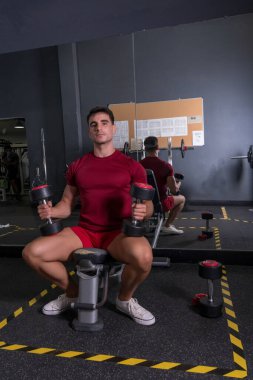 Mola zamanı. Spor kıyafetli genç adam spor salonunda oturuyor..