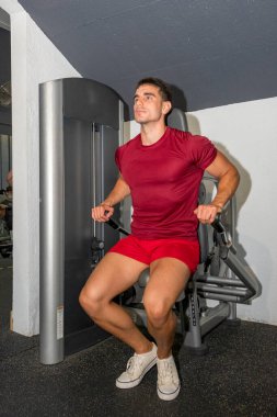 Genç vücut geliştirici trisepslerini makinede çalıştırıyor..