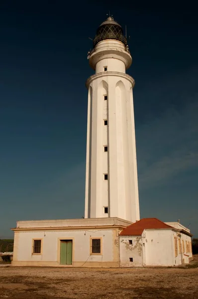 समुद्र तट पर या मुख्य भूमि पर स्थित एक लाइटहाउस या लाइट सिग्नलिंग टॉवर . — स्टॉक फ़ोटो, इमेज