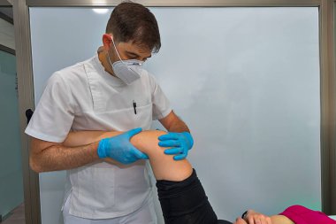 Doctor examines the knee of a girl.