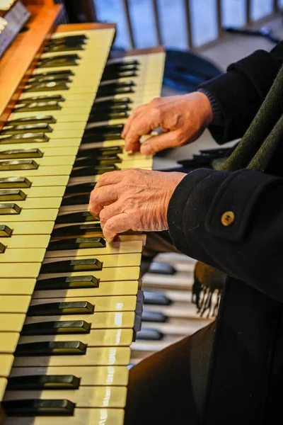 Mans hands playing a church organ