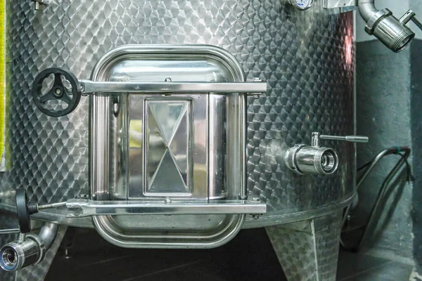 Stainless steel wine tank inside a cellar.