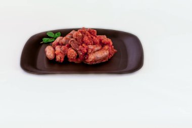 Kızarmış sosis ve domates sosu. Beyaz arka planda bir tabakta.