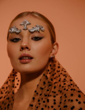 Sarışın bir kadın gibi güzel bir heykelin güzel stüdyo portresi. Mükemmel bir cilde, makyaja ve yüz sanatına sahip. Turuncu duvar arkasında çıplak poz veriyor.. 