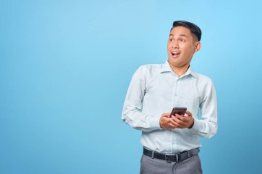 Heyecanlı genç yakışıklı iş adamı elinde akıllı bir telefonla yaratıcı bir fikir arıyor.