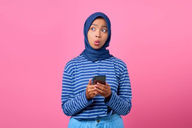 Şok olmuş genç Asyalı bir kadının portresi. Elinde cep telefonu, yana bakıyor.