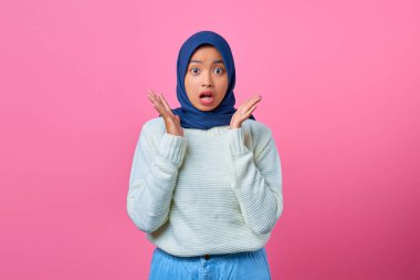 Pembe arka planda kameraya bakan şaşırmış genç Asyalı kadının portresi.