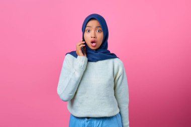 Pembe arka planda akıllı telefondan konuşan genç Asyalı kadının portresi.