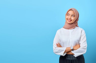 Boş uzaya bakarken kollarını kavuşturan neşeli Asyalı genç bir kadının portresi